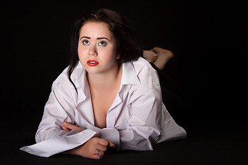 Image showing Portrait of long-haired woman in men's shirt lying on a black ba