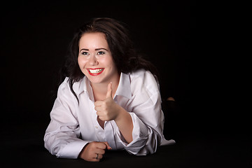 Image showing Portrait of long-haired woman in men's shirt lying on a black ba