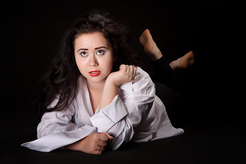 Image showing Portrait of long-haired woman in men's shirt lying on a black ba