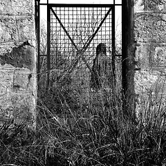 Image showing man behind vintage metal door and overgrown plants