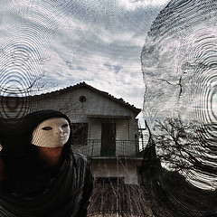 Image showing masked evil figure behind threaded window