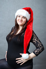 Image showing beautiful pregnant santa woman tenderly holding her tummy