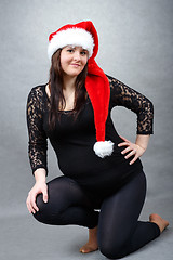 Image showing beautiful pregnant santa woman tenderly holding her tummy