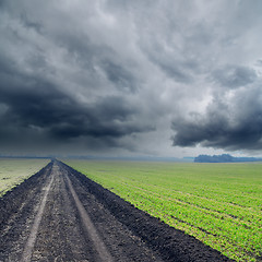 Image showing road in green fields to low rainy clouds