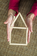 Image showing Hands holding model house made of wooden sticks