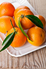 Image showing tangerines with leaves in plate 