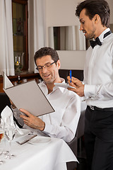 Image showing Waiter serving a couple in a restaurant
