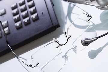 Image showing working place office desk table headset glasses telephone