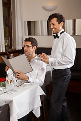 Image showing Waiter serving a couple in a restaurant