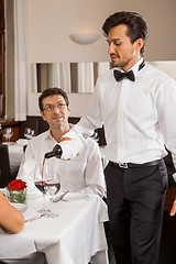 Image showing Waiter serving a couple in a restaurant