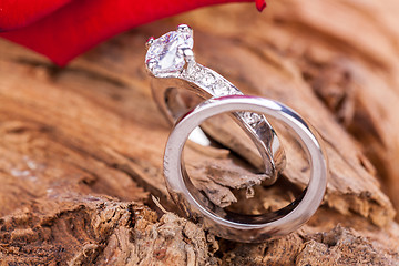 Image showing beautiful ring on wooden background and red rose