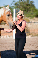 Image showing young woman training horse outside in summer