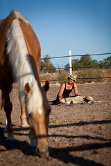 Image showing young woman training horse outside in summer