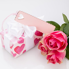 Image showing Gift box with an empty tag, next to three roses