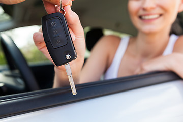 Image showing young smiling woman sitting in car taking key 