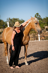 Image showing young woman training horse outside in summer