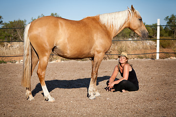 Image showing young woman training horse outside in summer