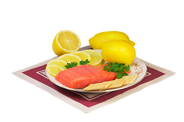 Image showing Salmon fillet and lemons on a platter on a white background.