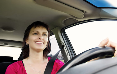 Image showing Smiling brunette woman driving car