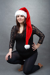 Image showing beautiful pregnant santa woman tenderly holding her tummy