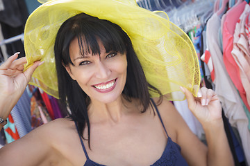 Image showing Pretty Italian Woman Trying on Yellow Hat at Market