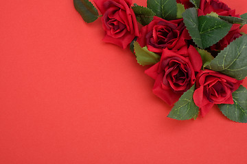 Image showing Red background with floral decor. Flowers are artificial. 