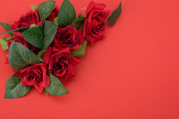 Image showing Red background with floral decor. Flowers are artificial. 