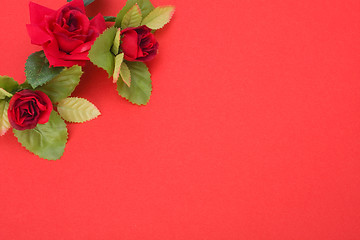 Image showing Red background with floral decor. Flowers are artificial. 