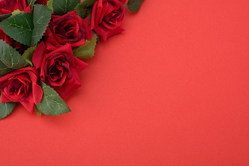 Image showing Red background with floral decor. Flowers are artificial. 