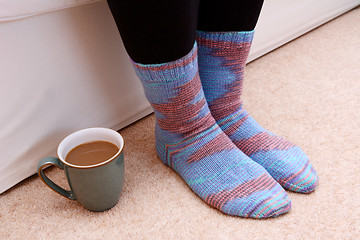 Image showing Hot drink on the floor by feet in socks