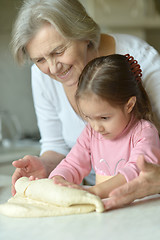 Image showing Little girl kneading dough with grandmother