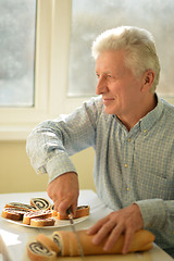 Image showing Senior man cutting pie