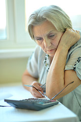 Image showing Serious elderly woman with calculator