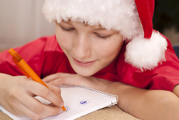 Image showing Boy in santa hat writing