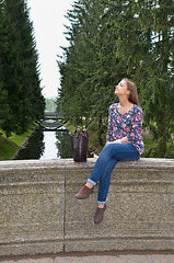 Image showing eautiful girl sits on an old stone bridge 