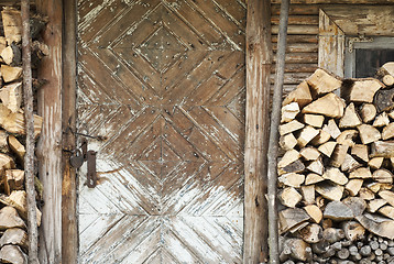 Image showing old door, firewoods beside the wall