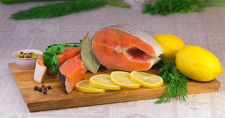 Image showing Fish salmon, lemon and greens placed on the table.