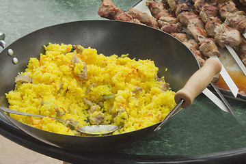 Image showing Pilaf in a large frying pan and grilled kebabs.