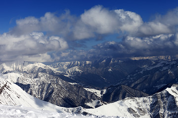 Image showing Sunlit winter mountains in clouds, view from off-piste slope