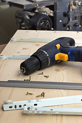 Image showing Furniture parts and electric screwdriver on wooden table