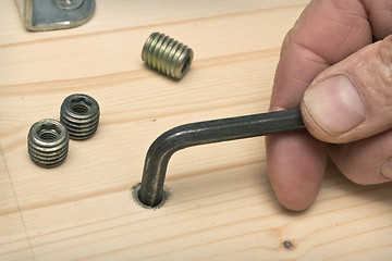 Image showing Screwing furniture fasteners in a wooden new shield