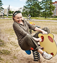 Image showing Young woman swinging on a baby swing