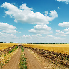 Image showing dirty road to horizon in field and clouds in blue sky