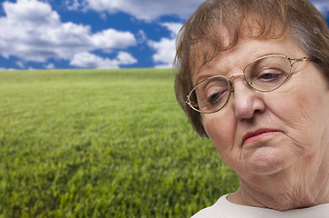 Image showing Melancholy Senior Woman with Grass Field Behind