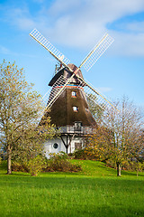 Image showing Traditional wooden windmill in a lush garden