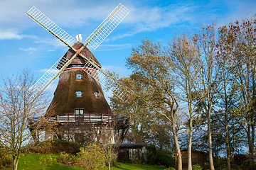 Image showing Traditional wooden windmill in a lush garden