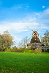 Image showing Traditional wooden windmill in a lush garden