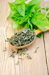 Image showing Basil green fresh and dry in a spoon on the board