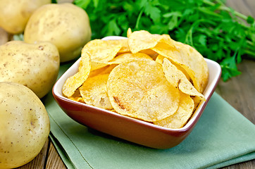Image showing Chips in a bowl with a potato on the board and napkin