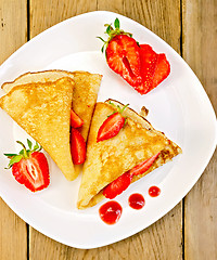 Image showing Pancakes with strawberries and jam on plate and board